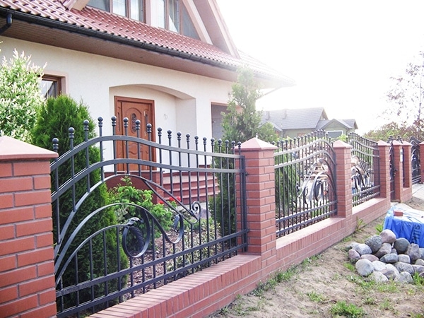 Einfamilienhaus mit schmiedeeisernem Zaun und Garten