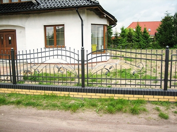 Einfamilienhaus mit dekorativem Metallzaun und Garten.