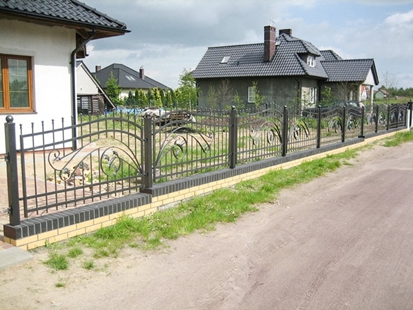 Schmiedeeiserner Zaun vor einem Einfamilienhaus