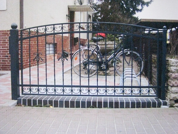 Schmiedeeisernes Tor mit Fahrrad im Hof.