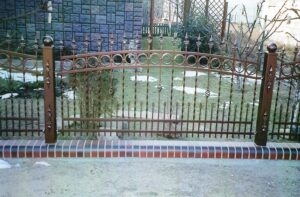 Verziertes Metallgartentor vor einem grünen Rasen.