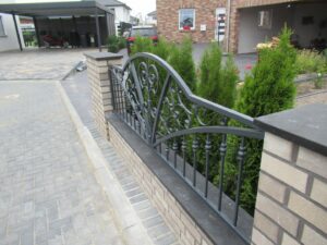 Elegantes schmiedeeisernes Geländer mit Ziegelmauer und Pflanzen.