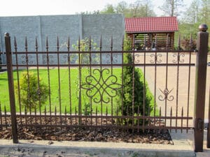 Verziertes Metallgittertor vor Garten.