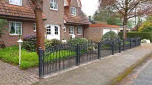 Einfamilienhaus mit Garten und schmiedeeisernem Zaun.