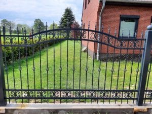 Verziertes Eisentor vor einem Haus.