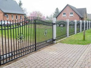 Schmiedeeisernes Tor vor Einfamilienhäusern.