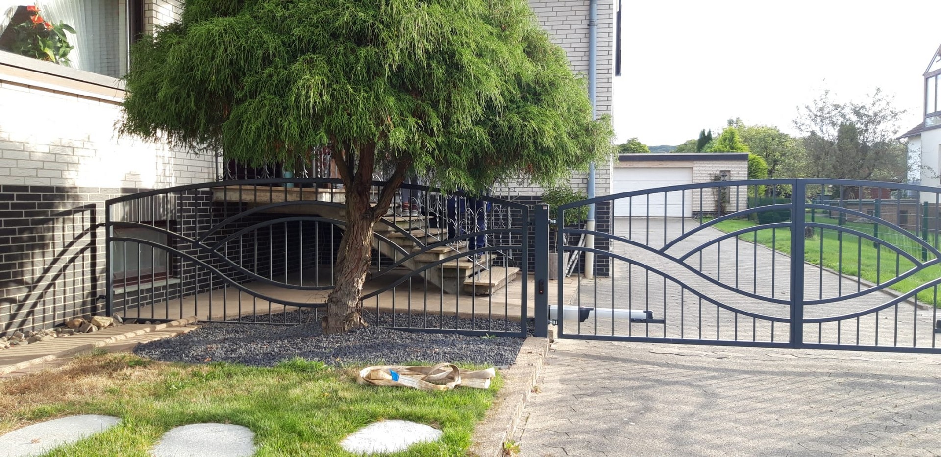 Eingangstor und Baum vor einem Wohnhaus.