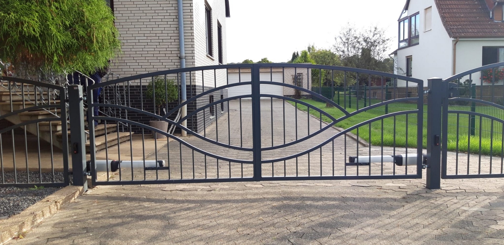 Schmiedeeisernes Tor vor einem Einfamilienhaus.