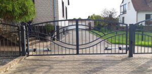 Schmiedeeisernes Tor vor einem Einfamilienhaus.