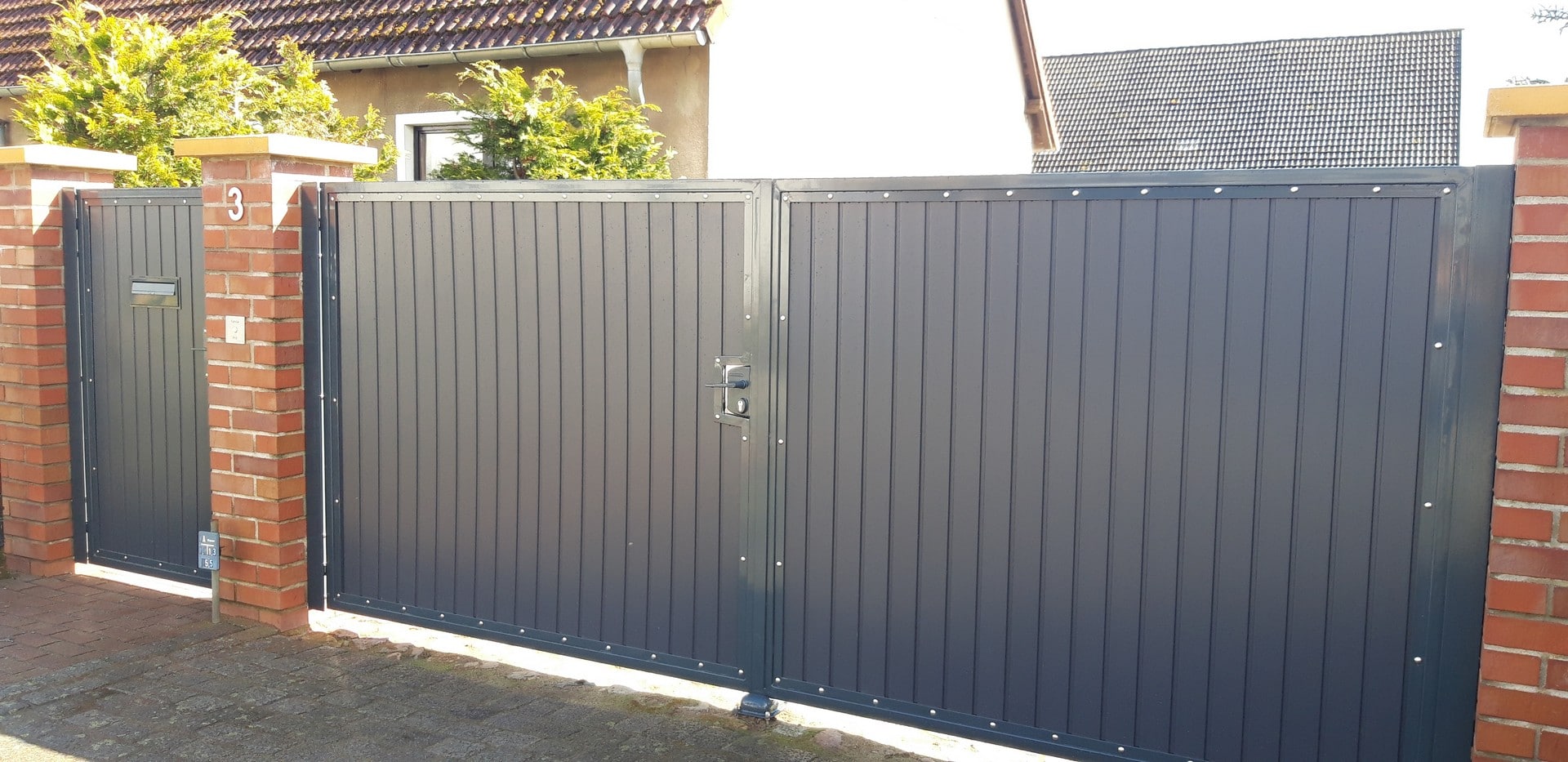 Graues Metalltor an einem Einfamilienhaus.