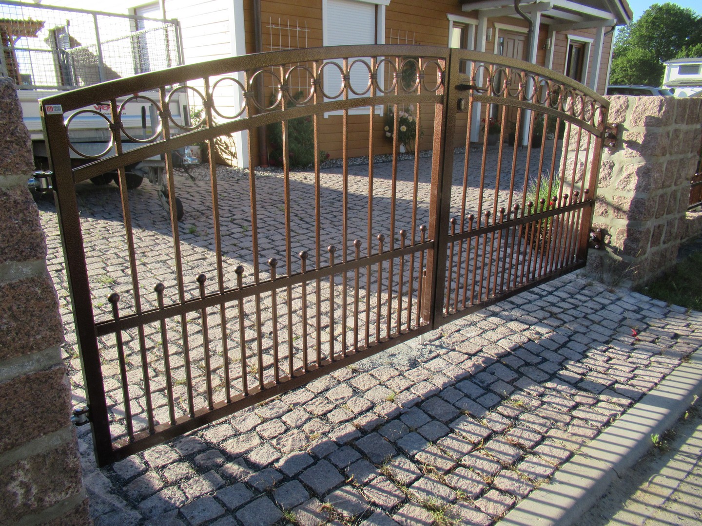 Schmiedeeisernes Tor vor einem Einfamilienhaus.