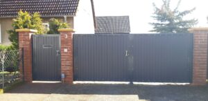 Zaun mit Tor aus Metall und Backsteinpfosten.