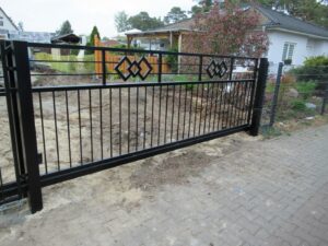 Schwarzes Tor vor Baustelle und Haus.