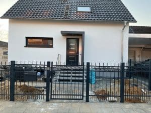 Einfamilienhaus mit Zaun und Eingangstor.