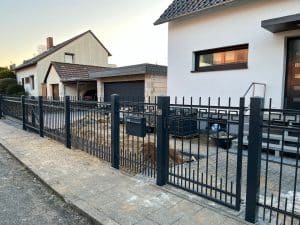 Einfamilienhaus mit schwarzem Metallzaun in der Dämmerung.