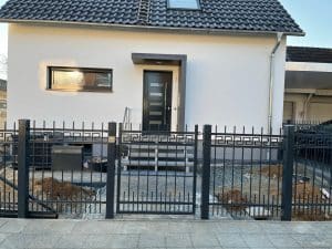 Einfamilienhaus mit Zaun und Eingangstreppe.