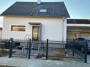 Einfamilienhaus mit Zaun und Auto in Einfahrt