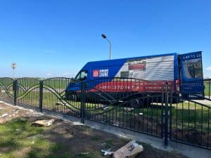 Werbe-LKW neben beschädigtem Metallzaun.