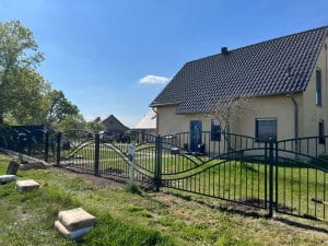 Haus mit Metallzaun und grünem Rasen.