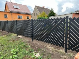 Moderner Holzzaun vor Häusern.