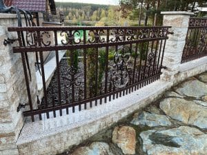 Dekoratives schmiedeeisernes Gartentor und Steinmauer.