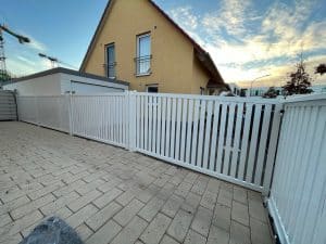 Haus mit weißem Zaun bei Sonnenuntergang.
