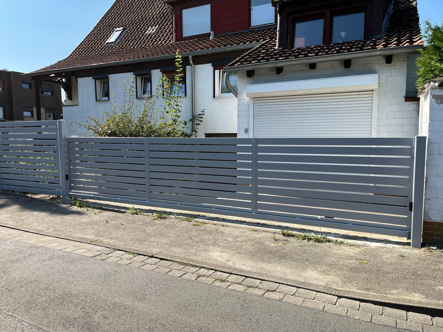 Graues Metalltor vor Einfamilienhaus.