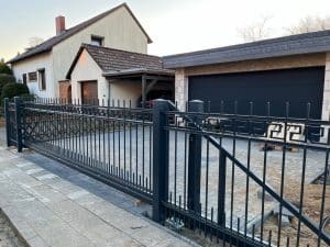 Einfamilienhaus mit Einfahrtstor und Garage bei Dämmerung.