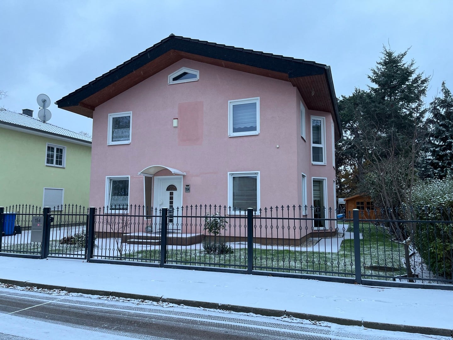 Rosa Einfamilienhaus mit Schnee und Zaun.