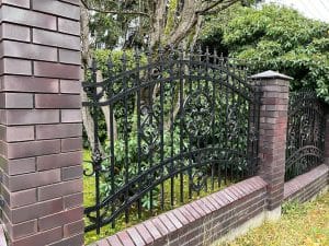 Eisernes Gartentor mit Verzierungen und Backsteinpfosten