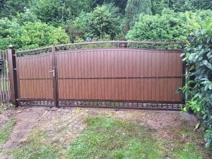 Klassisches Doppelflügeltor in Holzoptik mit dekorativen Elementen, hergestellt von KOMABUD.