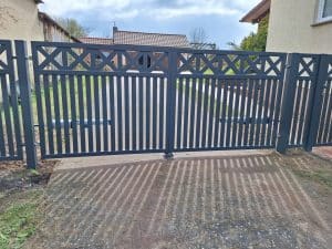 Modernes Doppelflügeltor mit vertikalen Stäben und dekorativem Kreuzmuster, hergestellt von KOMABUD.