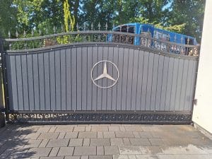 Stilvolles graues Schiebetor mit dekorativen Verzierungen und Metalllogo, hergestellt von KOMABUD.