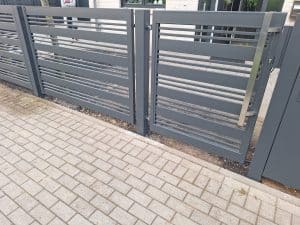 Moderne Metallpforte mit horizontalen Lamellen und Edelstahlgriff, hergestellt von KOMABUD.
