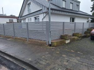 Moderner silberner Metallzaun mit horizontalen Lamellen als Sichtschutz, hergestellt von KOMABUD.
