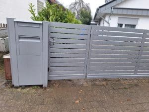 Moderne silberne Metallpforte mit horizontalen Lamellen und integriertem Briefkasten, hergestellt von KOMABUD.