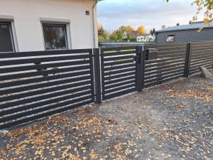 Moderner Metallzaun mit horizontalen Lamellen, Eingangspforte und integriertem Briefkasten, hergestellt von KOMABUD.