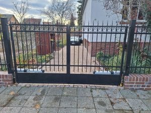 Schmiedeeisernes Doppelflügeltor mit dekorativen Elementen und elektrischem Antrieb, hergestellt von KOMABUD.